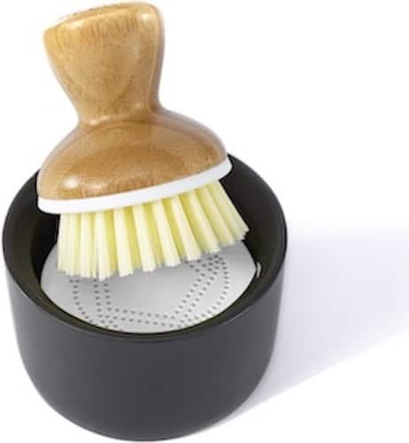 Kitchen cleaning brush with wooden handle in black holder for easy cleaning.