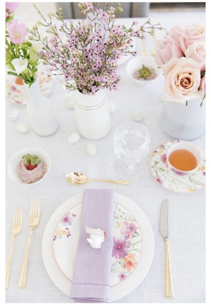 Table setting featuring a lavender napkin, floral plates, and vases with fresh flowers, creating a cheerful spring atmosphere.
