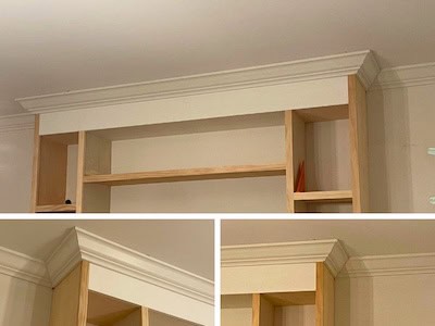 Close-up view of the top section of a wooden bookshelf with a decorative crown molding.