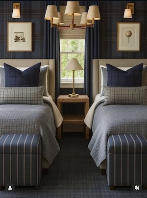A stylish bedroom featuring two twin beds with various patterned blue and gray bedding, nightstand with a lamp, and artwork on the walls.