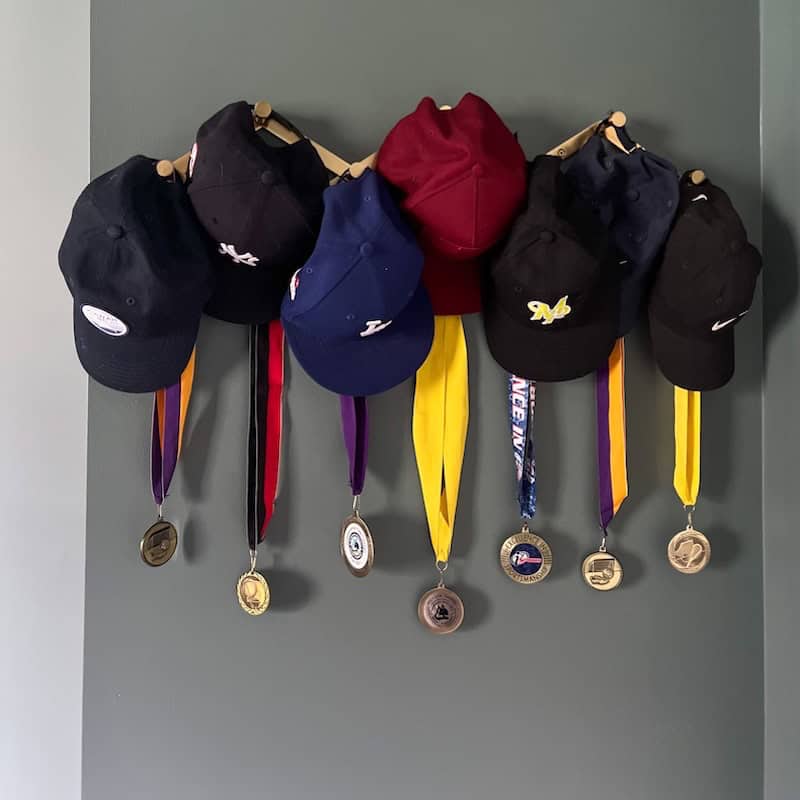 A collection of various baseball caps and medals hanging on a wall, showcasing achievements and memorabilia.