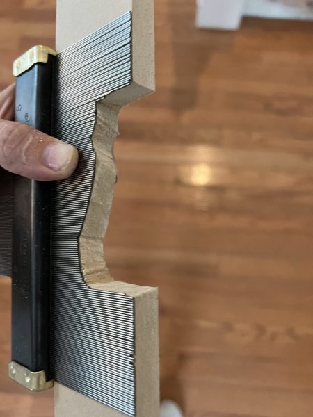 Final result of the jig saw cut showing the neatly shaped MDF profile that wraps around the newel post, illustrating the successful application of trial and error techniques with scrap pieces.