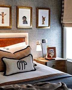 A stylish bedroom featuring a bed with decorative pillows, a bedside table with a lamp and framed animal art on the wall.