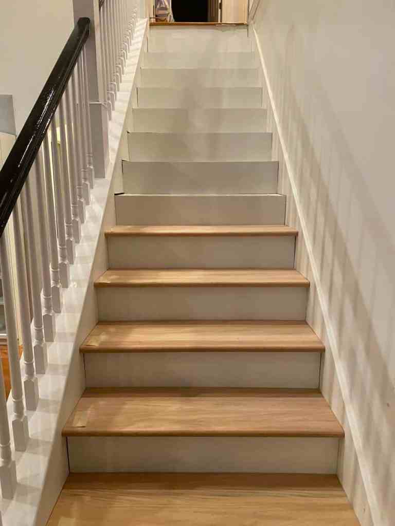 A view of a staircase with wooden steps and white railings, leading to the upper floor.