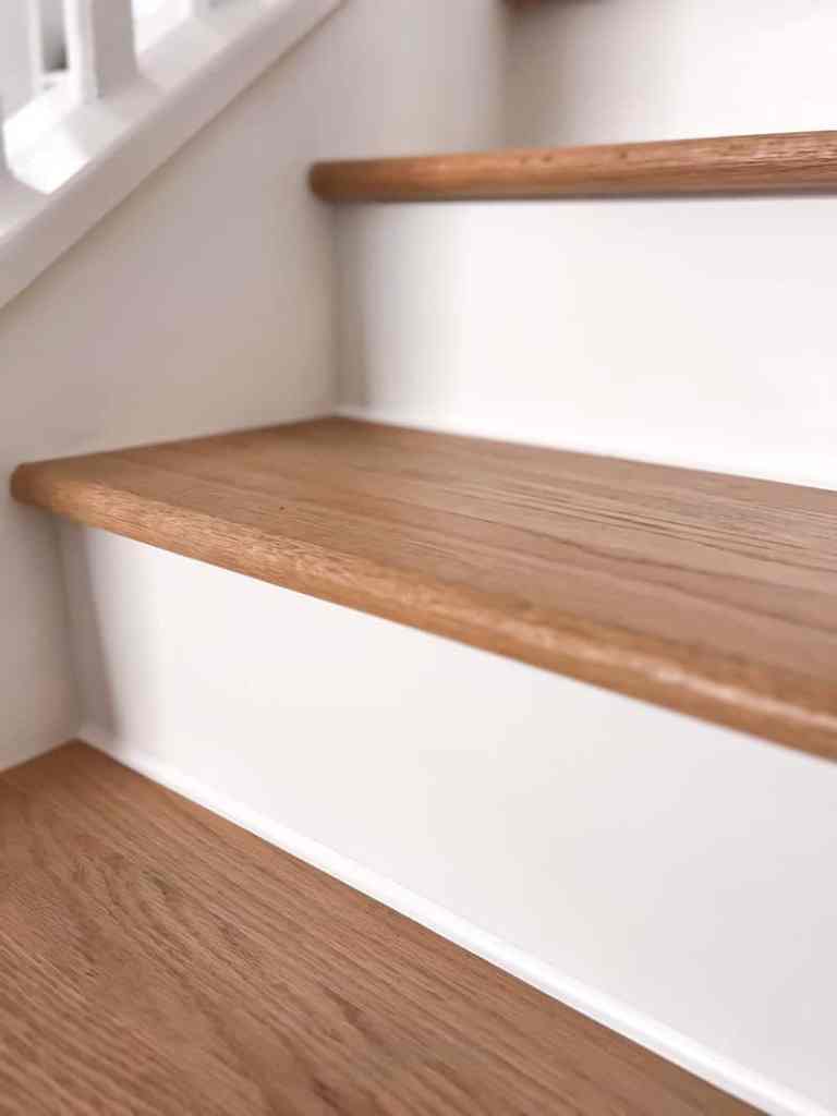 Close-up view of wooden staircase steps with a clean white railing.