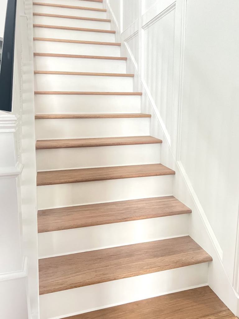 A staircase with wooden steps and white walls, featuring a modern design and natural light.
