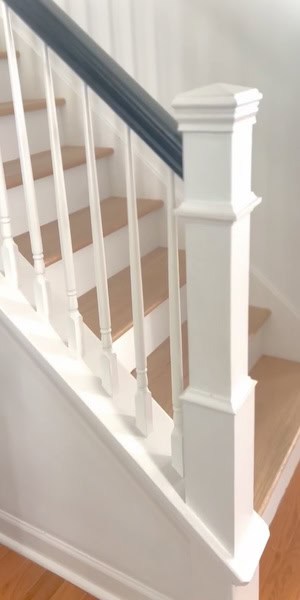 A close-up view of a staircase with white railings and wooden steps.