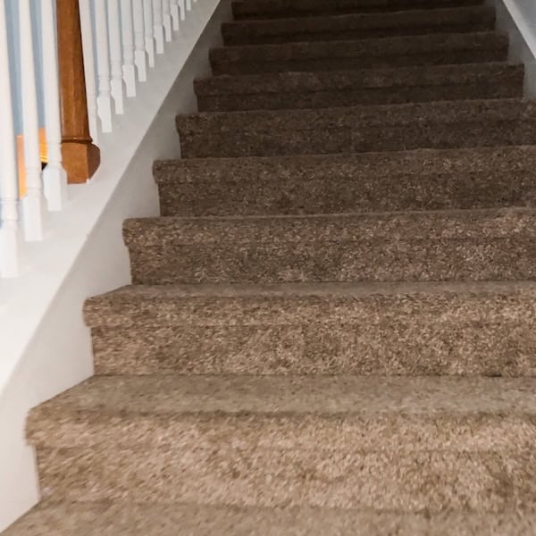 Carpeted staircase leading upward with white railing