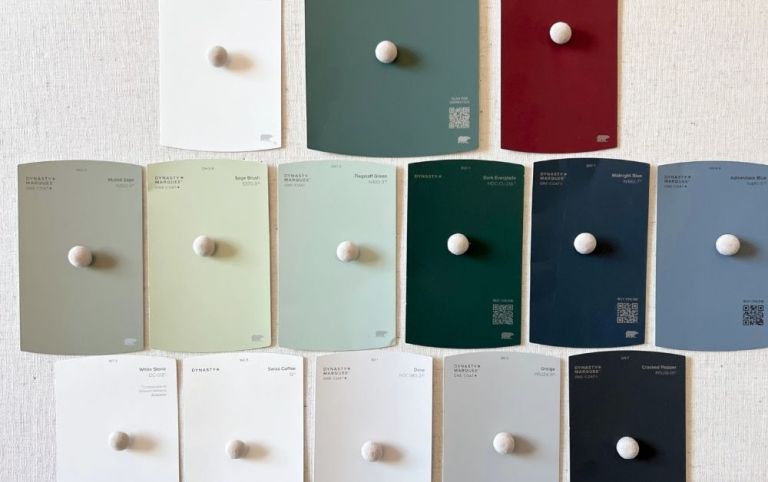 A display of various paint color swatches arranged on a light background, featuring shades like white, green, blue, and burgundy, each with a label indicating the color name and code.