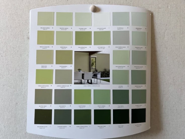 A color palette featuring various shades of green paint samples arranged in a grid format, with a centered image showcasing a modern outdoor space.