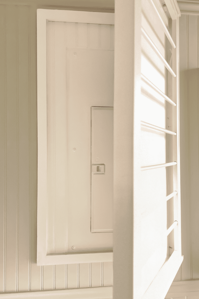 an image showing a clothes drying rack hiding a electrical panel containing fuse boxes in laundry room