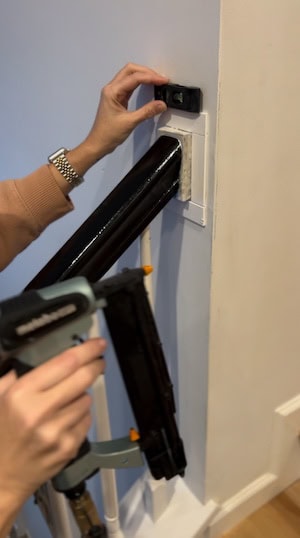 Attaching PVC lattice to the staircase with a nail gun and mini level for precision during a DIY upgrade. Learn how to upgrade a staircase easily and affordably