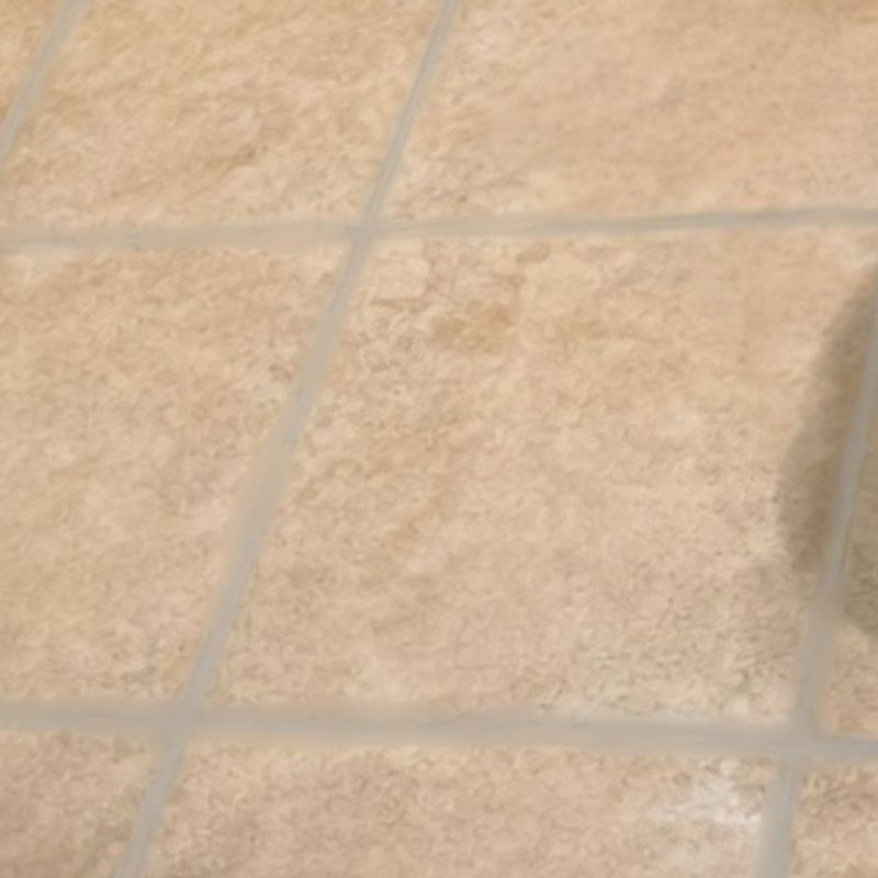 Close-up of a light-colored tiled floor with visible grout lines.