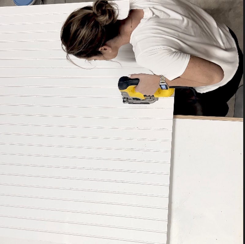 Using a jigsaw to cut a white wall paneled board
