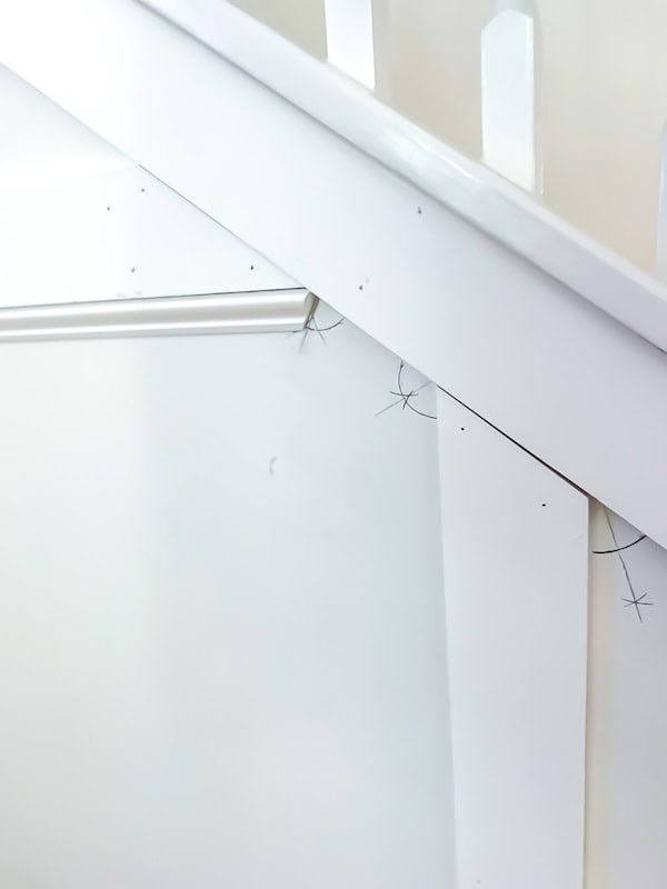 Close-up view of a white staircase wall with a handrail and minor scuff marks.