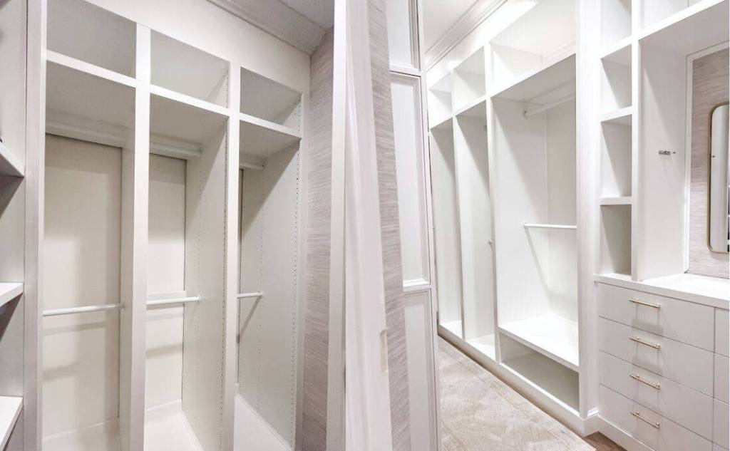 Empty custom walk-in closet with built-in shelving, dresser, and vanity wall after renovation.
