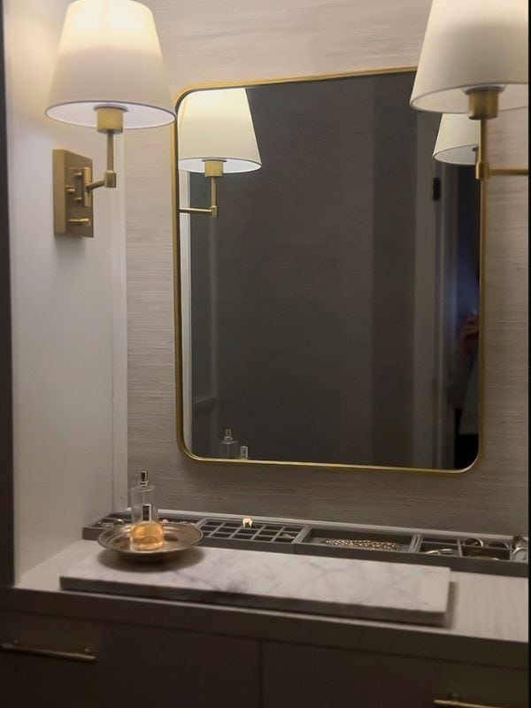 After photo of a  renovated narrow primary walk-in closet vanity area with a built-in dresser, updated lighting, jewelry trays and a mirror