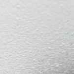 Close-up of a spray-painted surface covered in a rough, grainy texture caused by overspray or dust contamination.