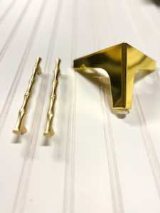Three small decorative items on a striped surface: two golden hairpins and a gold geometric-shaped clip.