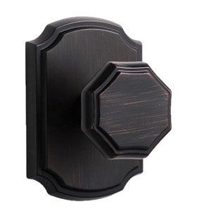 A decorative octagonal door knob in an oil-rubbed bronze finish, mounted on a rectangular backplate.