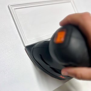 A person using a detail sander on a white surface, focusing on intricate areas.