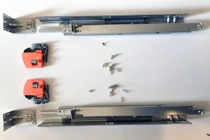 Image showing soft close dampers and metal rail components for cabinet installation.