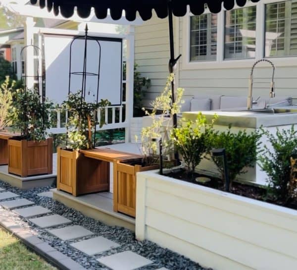 A transformed backyard featuring a decorative outdoor area with planters, stone pathways, and cozy seating arrangements surrounded by lush greenery.