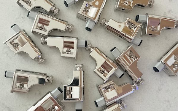 A collection of ROK universal soft close dampers, featuring a shiny metallic finish, arranged on a light-colored surface.