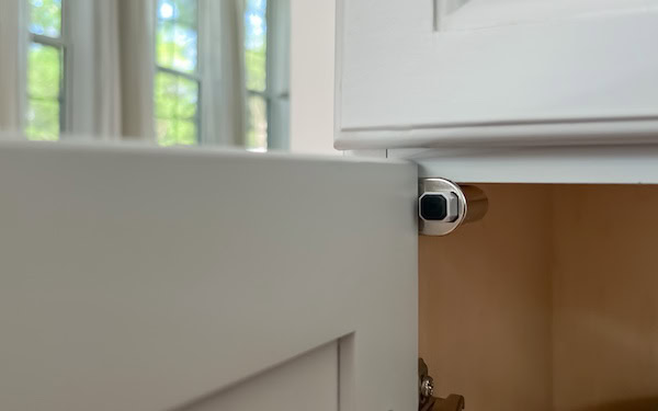Close-up of a soft close damper installed inside a cabinet, showing the mechanism near the hinge area.