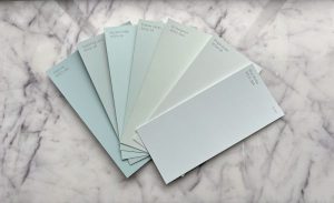 A selection of paint color swatches arranged on a marble surface, featuring various shades of blue and green for a painting checklist.