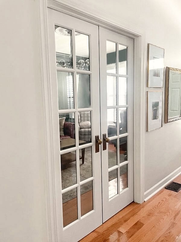White interior French doors in entryway hallway with antique knobs with long backplate