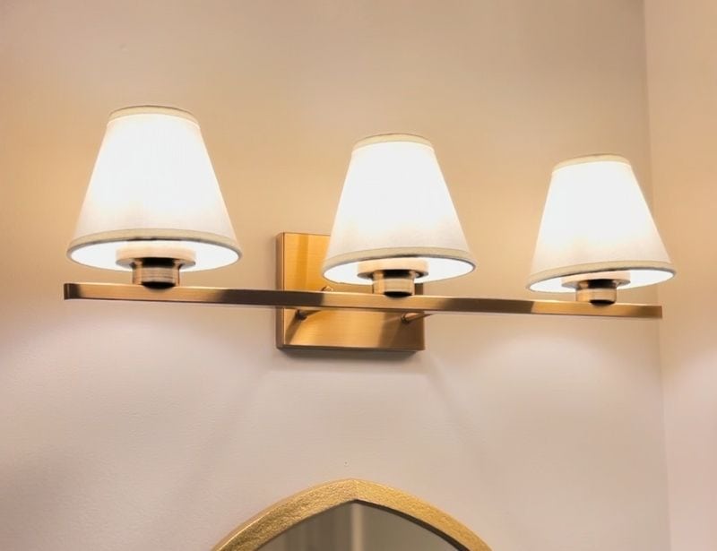 Close-up lifestyle photo of linen-shade vanity lighting creating a soft, warm glow in the bathroom.