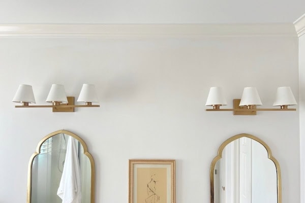 Modern bathroom vanity light fixtures with white shades and gold accents.