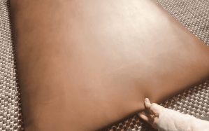 A person holding a piece of faux leather material, preparing it for a DIY headboard project.
