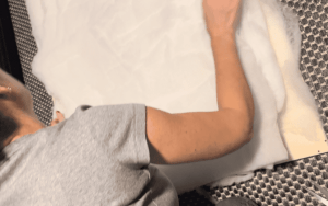 A person is laying out batting material on a flat surface while preparing to create a DIY upholstered headboard.