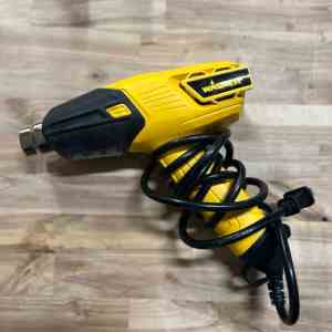 Close-up of a yellow Wagner heat gun with a curled power cord, placed on a wooden surface.