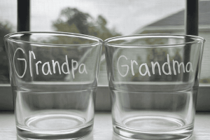 Two glass containers labeled 'Grandpa' and 'Grandma' placed side by side on a windowsill.