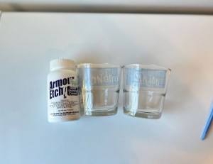 Bottle of Armor Etch cream next to two etched glass cups labeled 'Grandma' and 'Grandpa'.