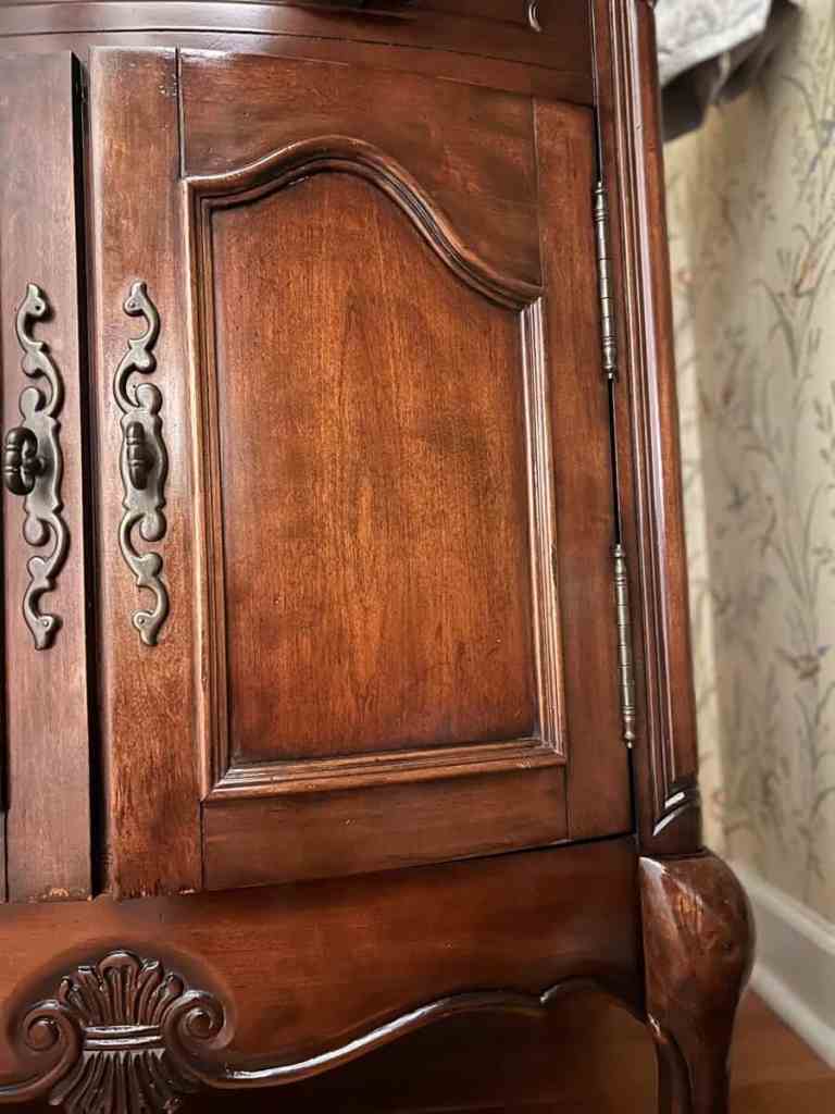 Close-up view of a wooden cabinet door featuring detailed metal handles and rich wood grain.
