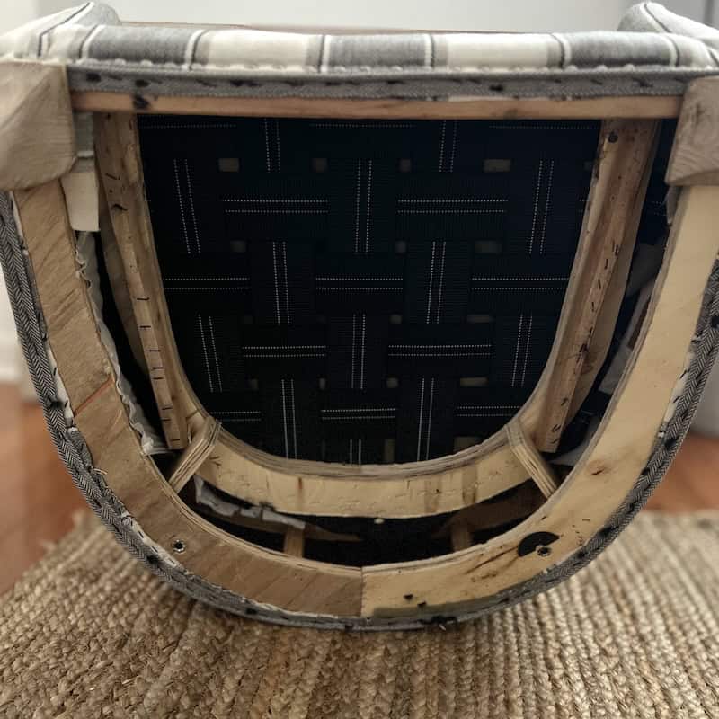 Underside view of a chair, showing the frame and woven fabric support beneath the seat.