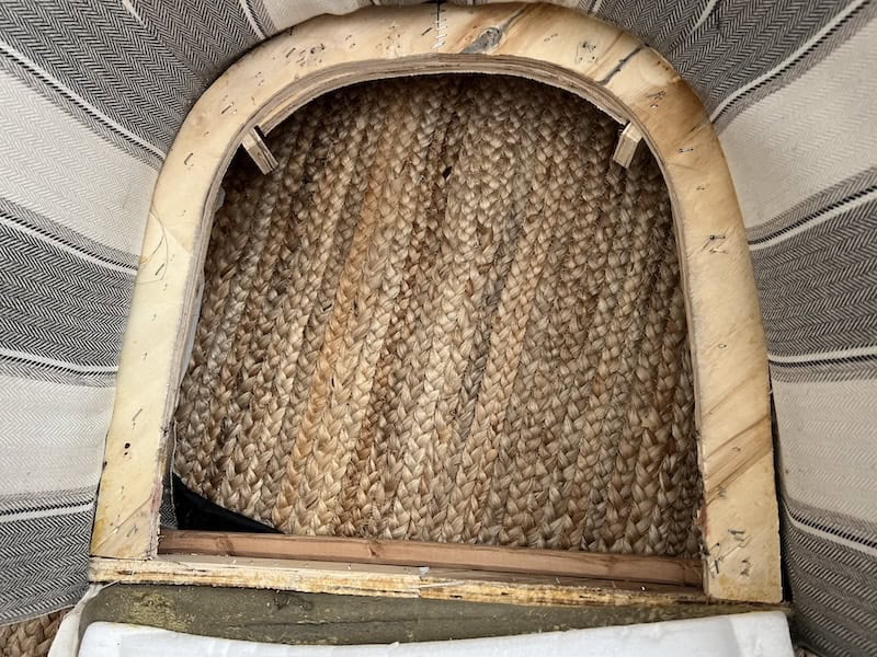 Close-up view of a wooden chair's underside, showing woven rush seating and the frame structure.