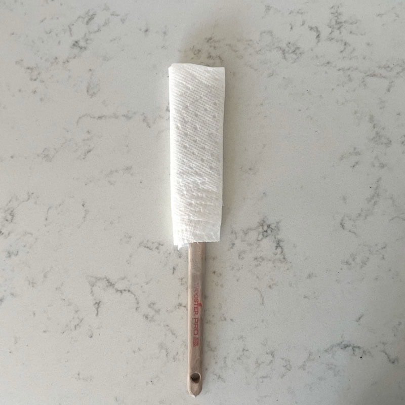 A paint brush wrapped in a warm white paper towel to try to soften paint