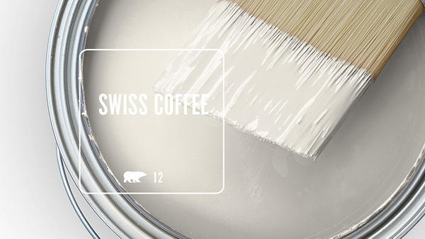 Close-up of a paint can with white paint and a brush, labeled 'SWISS COFFEE.'