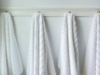Four white towels hanging neatly on a wall-mounted rack.