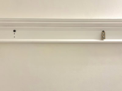 Close-up of a white wall with a simple picture hanging rail installed near the top.