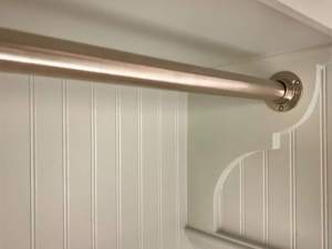 Close-up of laundry room hanging rod with decorative wood bracket support
