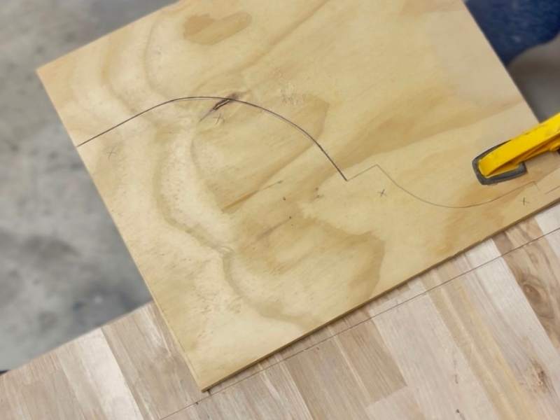 Clamping wood board to work surface before cutting decorative bracket with jigsaw