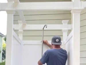 Installing outdoor shower enclosure with a metal shower head and privacy panels.