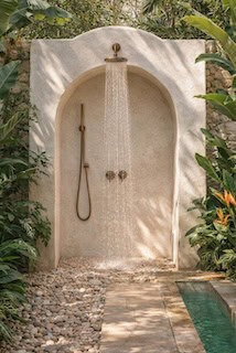 Mediterranean outdoor shower with arched plaster niche, rainfall showerhead and pebble stone floor