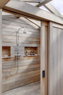 Wood outdoor shower with built-in storage niches, rainfall showerhead and overhead privacy structure